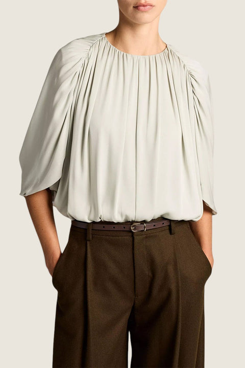 Bolina Vince stone sage gathered cape bubble blouse with a soft sheen, worn tucked into dark brown trousers.
