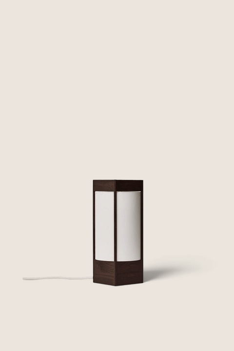 Bolina Andon table lamp in dark brown ash wood with a cylindrical white shade and minimalist sculptural design.