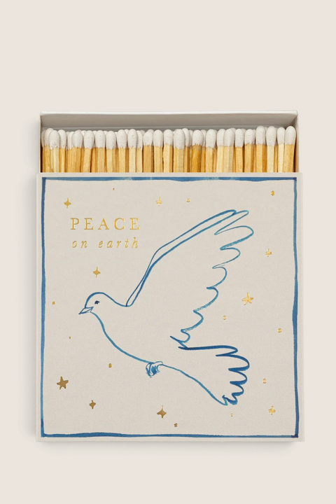 Bolina Archivist matchbox featuring a blue line-art peace dove and gold foil stars on a cream background